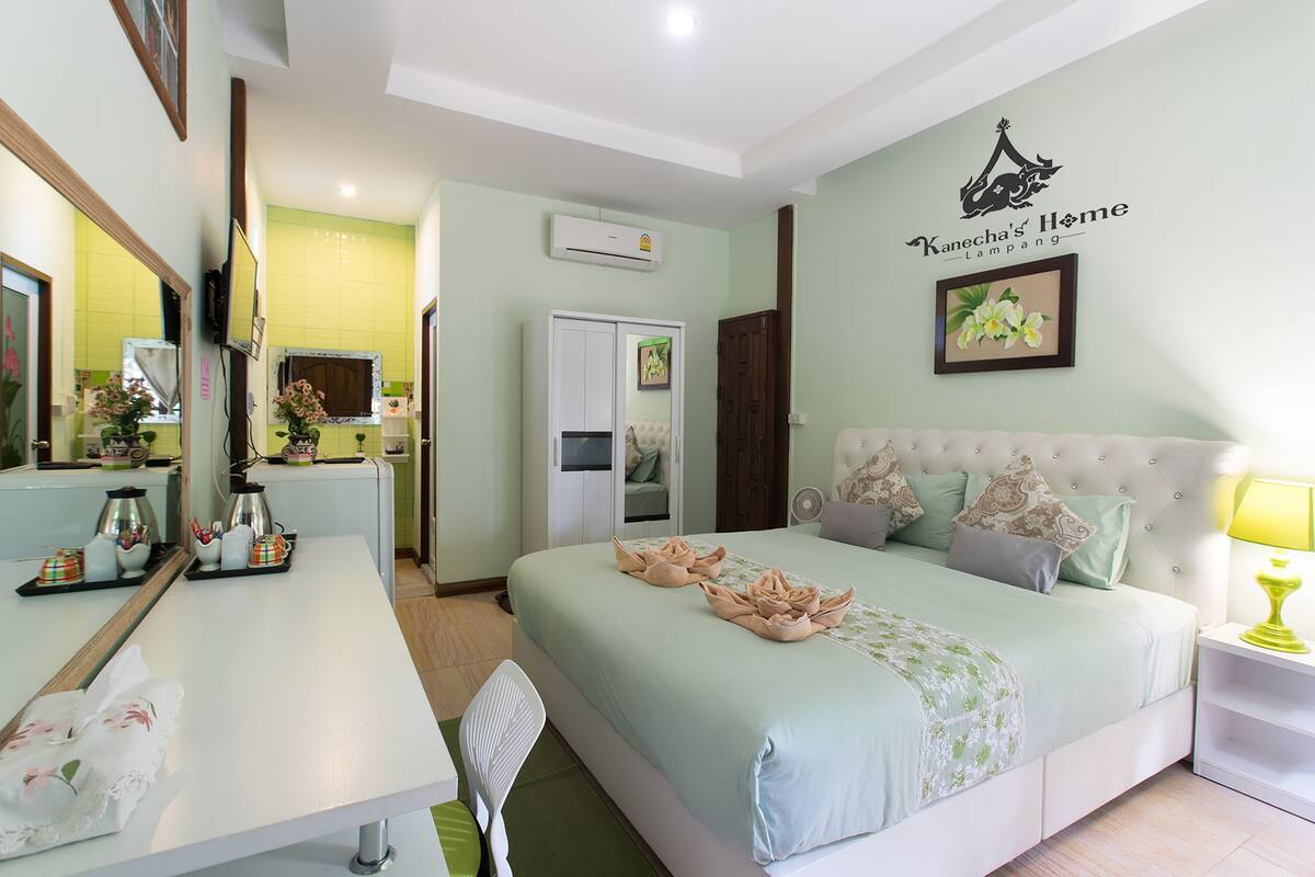 A hotel room with a bed, bedside table, chair, and a desk with a mirror.