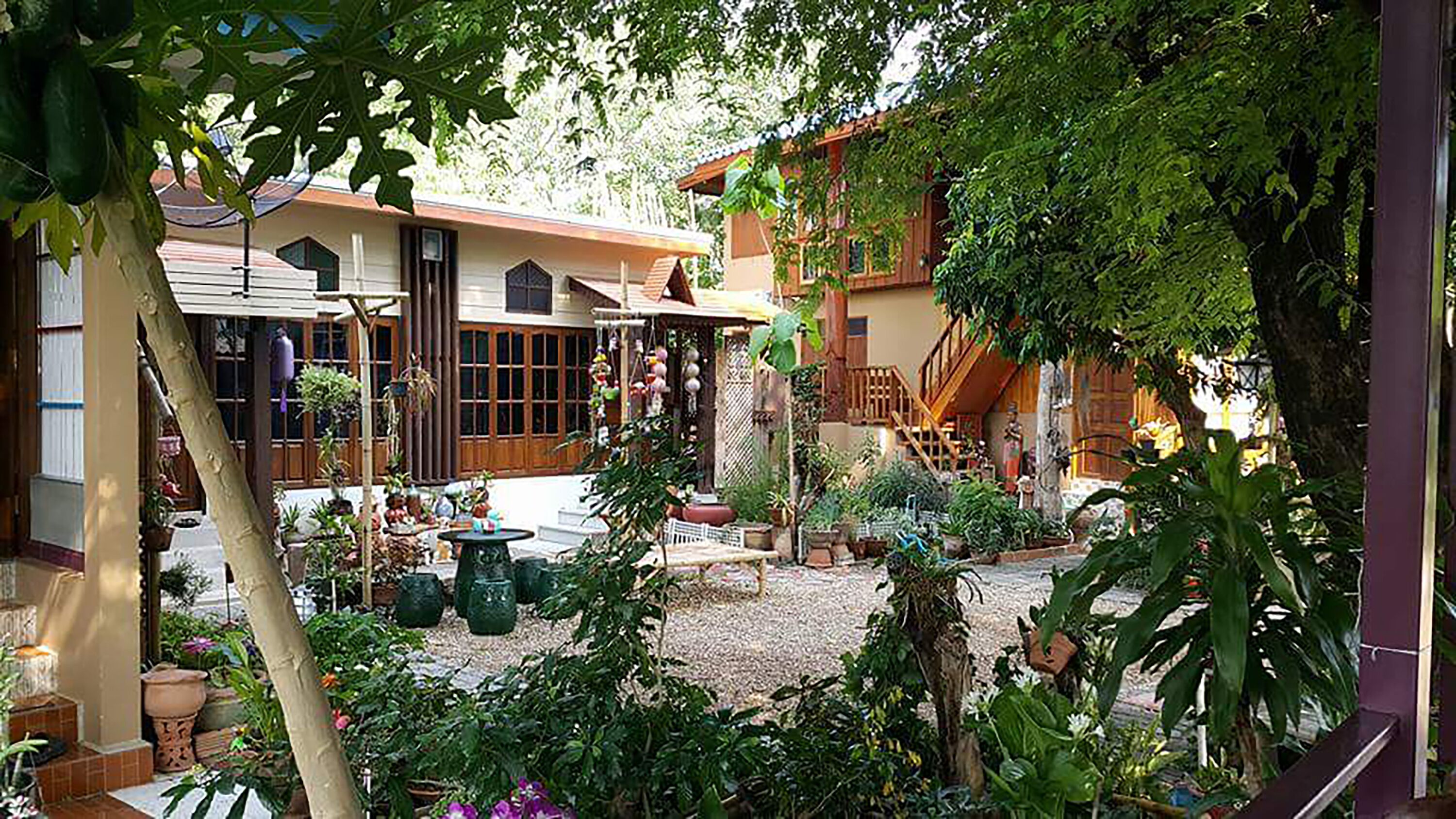 A courtyard with a traditional house, potted plants, and a small fountain.
