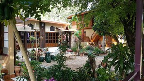 Une cour avec une maison de style traditionnel, des plantes en pot et une petite fontaine.