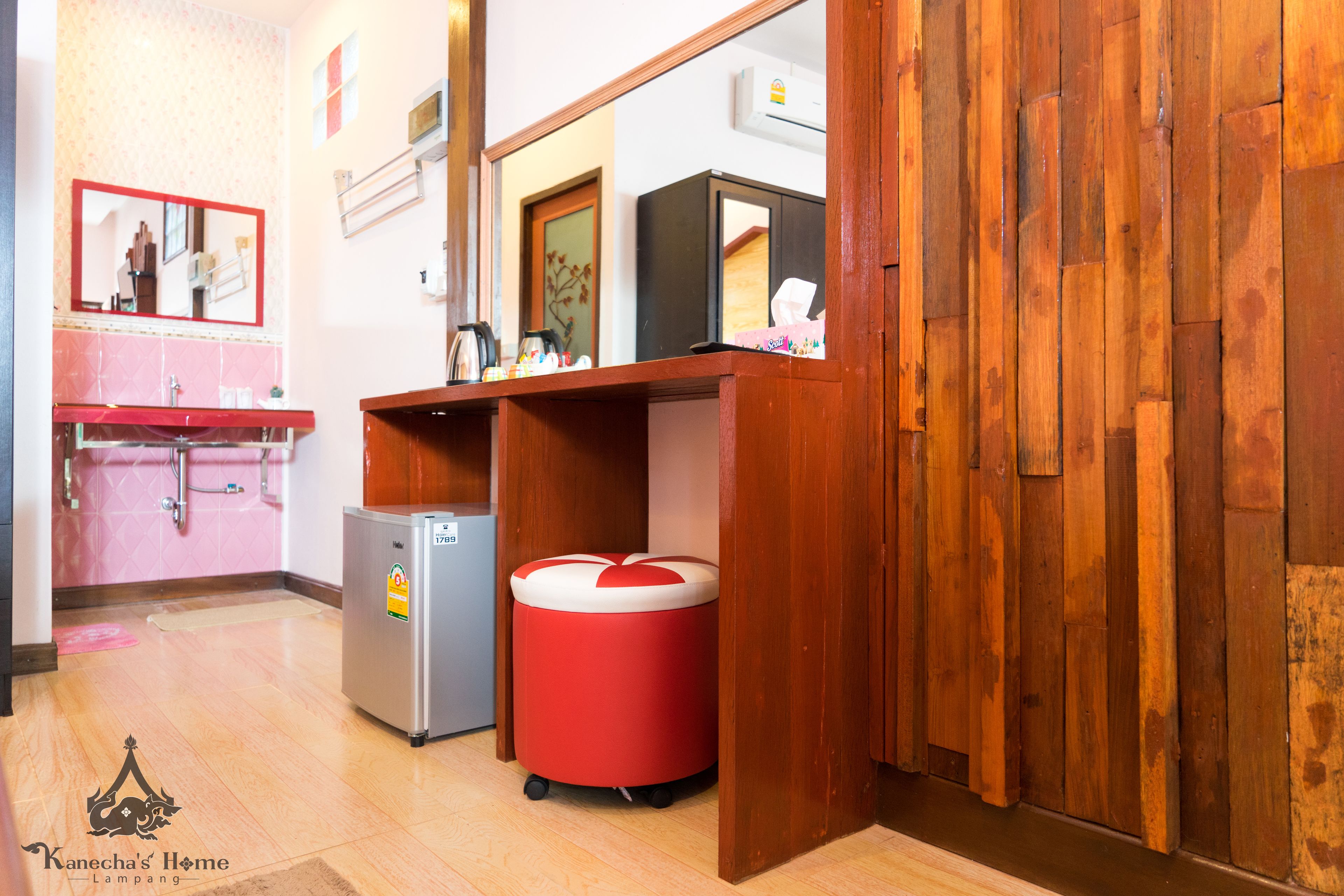 A compact kitchen with a sink, a refrigerator, and a red trash bin.