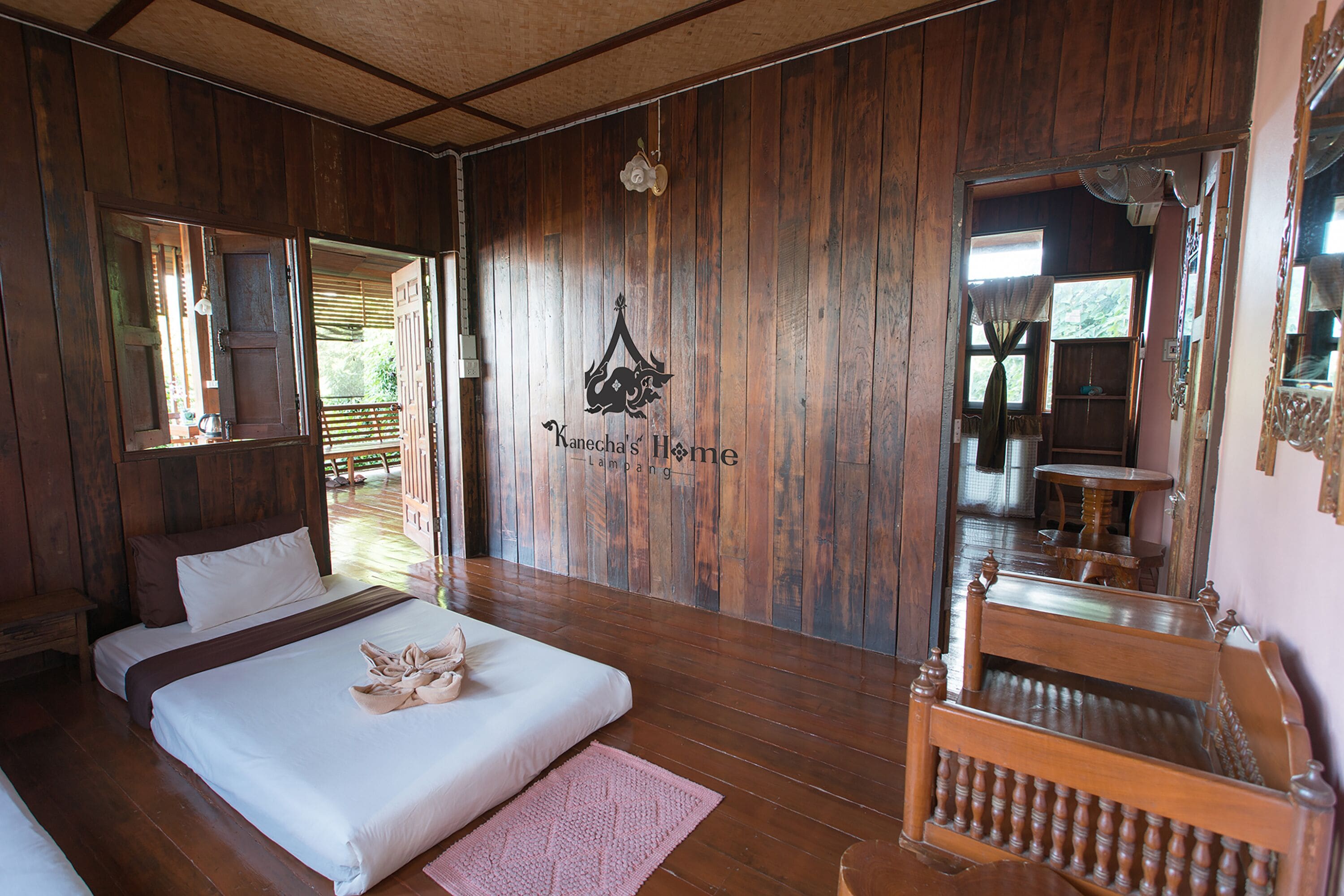 A wooden-floored bedroom with a bed, a nightstand, and a mirror.