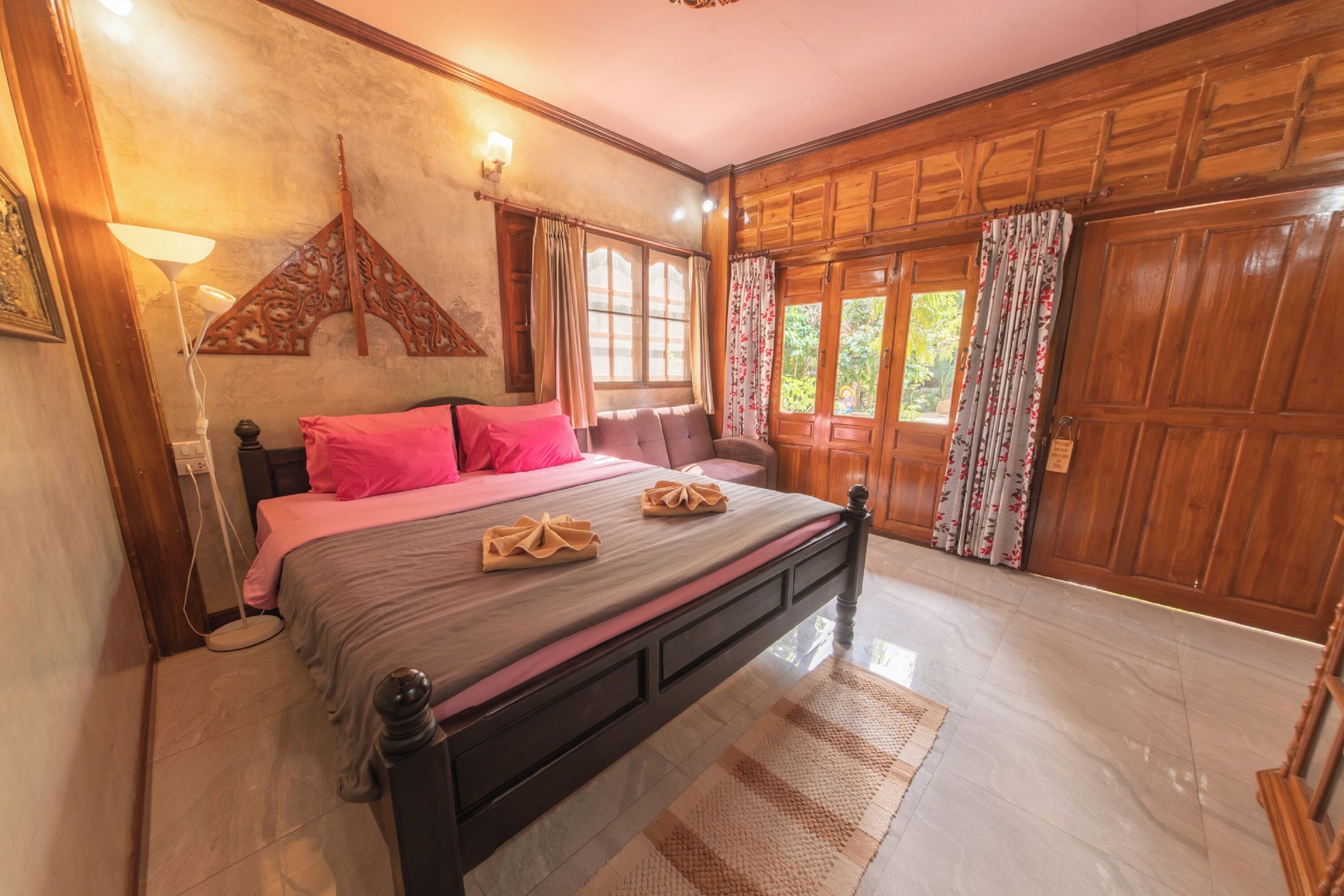 Een slaapkamer met een houten bed, roze beddengoed en een decoratieve wandhanger.