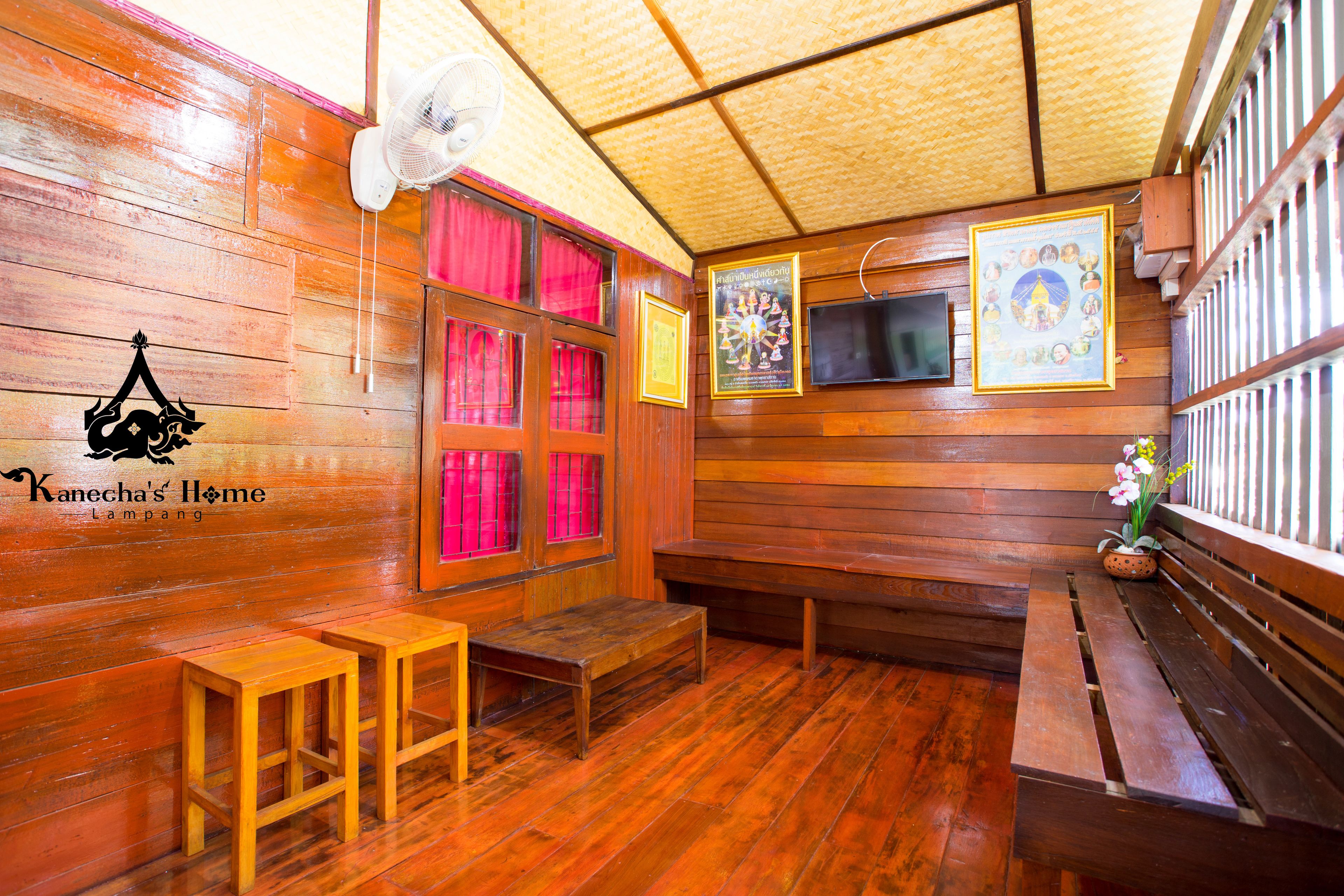 Interior de madera con un abanico, bancos y una pared decorada con fotografías enmarcadas.
