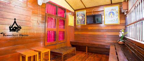 Interior de madera con un abanico, bancos y una pared decorada con fotografías enmarcadas.