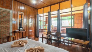 A room with a bed, wooden furniture, a TV on a stand, and large windows. - Kanecha's Home (Lampang)