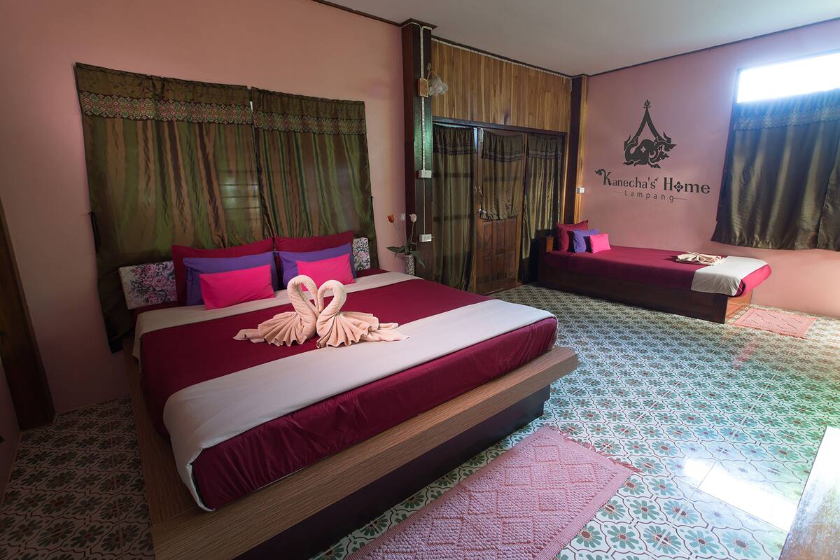 A hotel room with a large bed, a smaller bed, and a wardrobe.