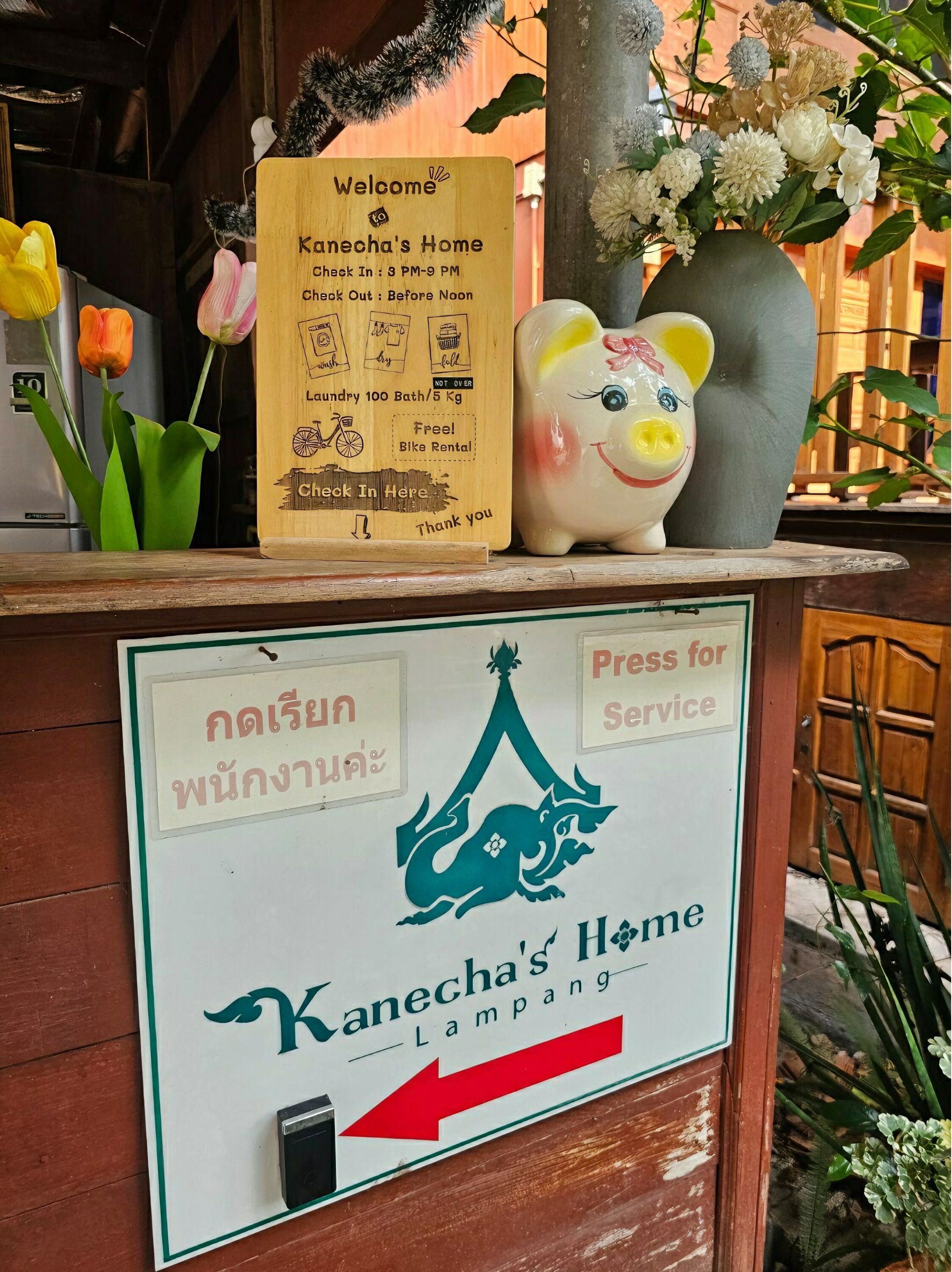 Segnale di benvenuto per Kanecha's Home con orari di check-in e check-out, servizio di lavanderia e noleggio biciclette, e servizio di stiratura.