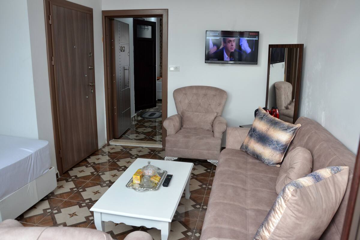 Ein Wohnzimmer mit einer Couch, einem Sessel und einem Couchtisch mit Fernbedienungen und Snacks.