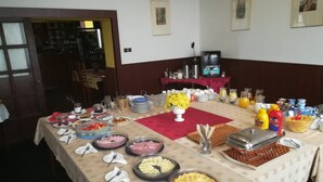 A buffet setup with various food items, serving utensils, and condiments on a table. - Hotel Isora (Ostrava)