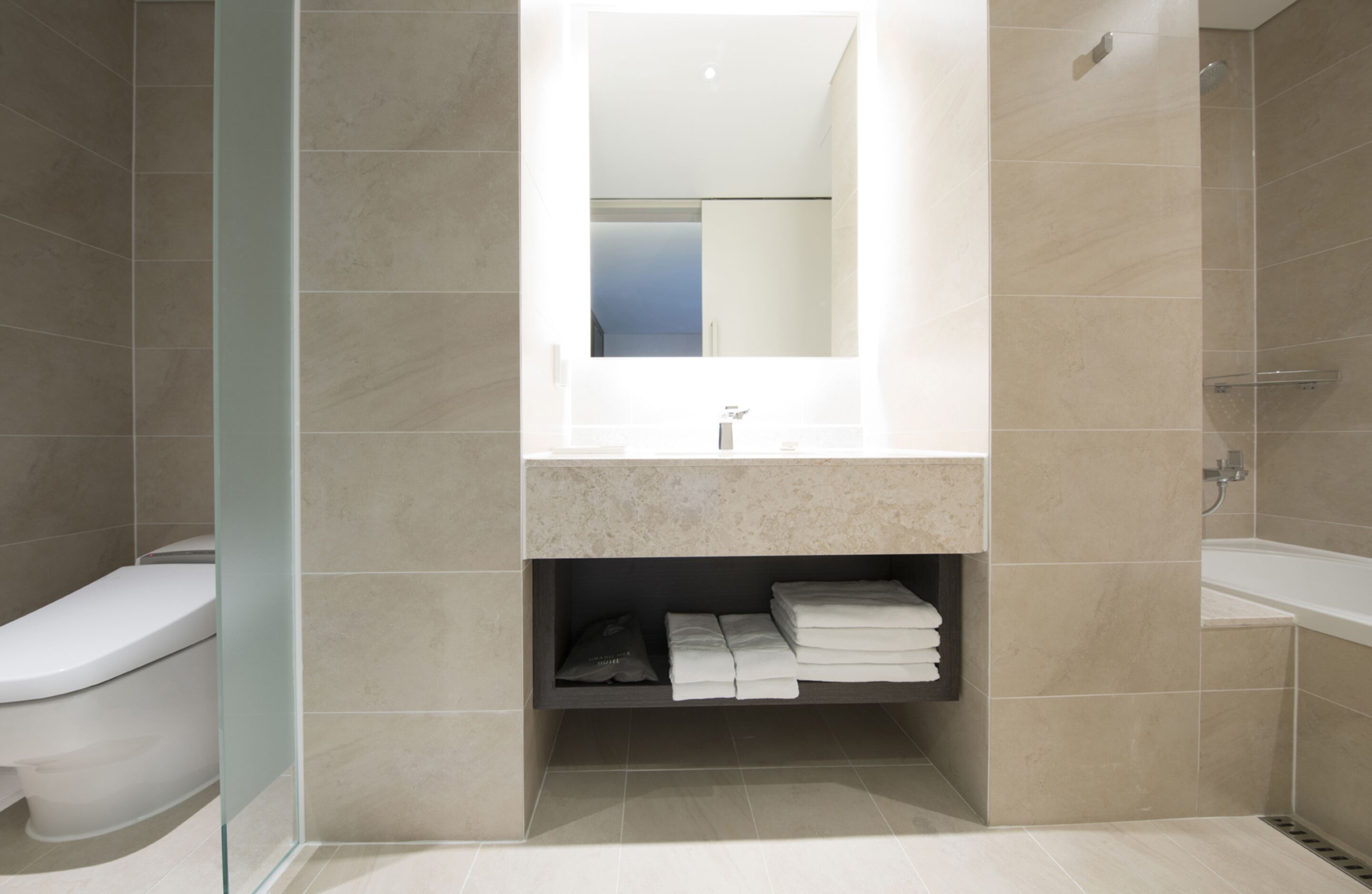 A modern bathroom with a glass shower enclosure, a built-in sink, and a vanity with a mirror.