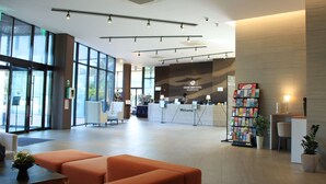 A spacious lobby with a reception desk, seating area, and a large window providing natural light. - Grand Mer Hotel Jeju (Seogwipo)