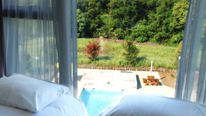 A hotel room with a view of a swimming pool and outdoor seating. - Grand Mer Hotel Jeju (Seogwipo)