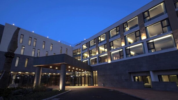 A modern hotel with a covered entrance, multiple floors, and a well-lit facade. - Grand Mer Hotel Jeju (Seogwipo)