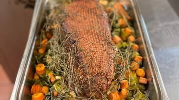 A roasted turkey surrounded by vegetables in a metal roasting pan.
