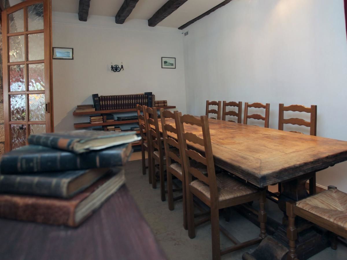 A dining room with a wooden table and chairs, surrounded by books.