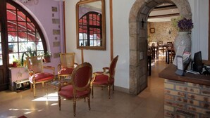 Un coin repas avec une table ronde et des chaises, un miroir au mur et une arche donnant sur une autre pièce.