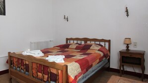 Une chambre à coucher avec un lit en bois, une table de chevet avec une lampe et un radiateur.
