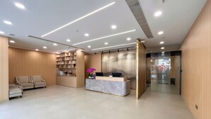 A modern reception area with a marble counter, a sofa, and a decorative plant. - Shanghai Joyful Star Hotel (Shanghai)