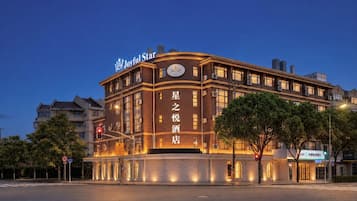 A hotel with a curved facade, illuminated signage, and a clear sky.