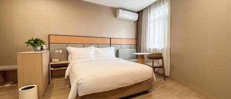 A hotel room with a bed, bedside table, lamp, and a small table with a chair.