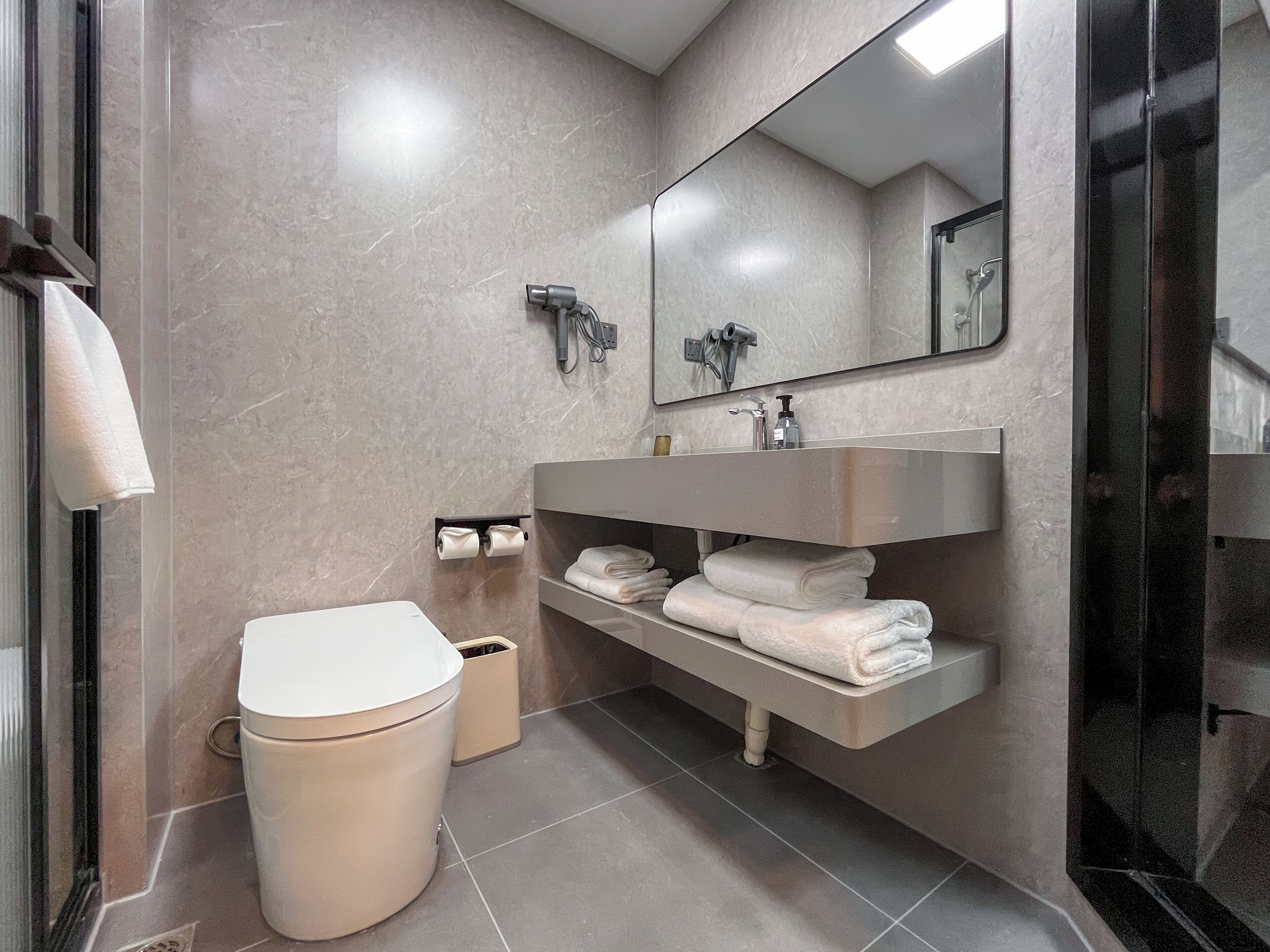 Een moderne badkamer met toilet, wastafel en spiegel.
