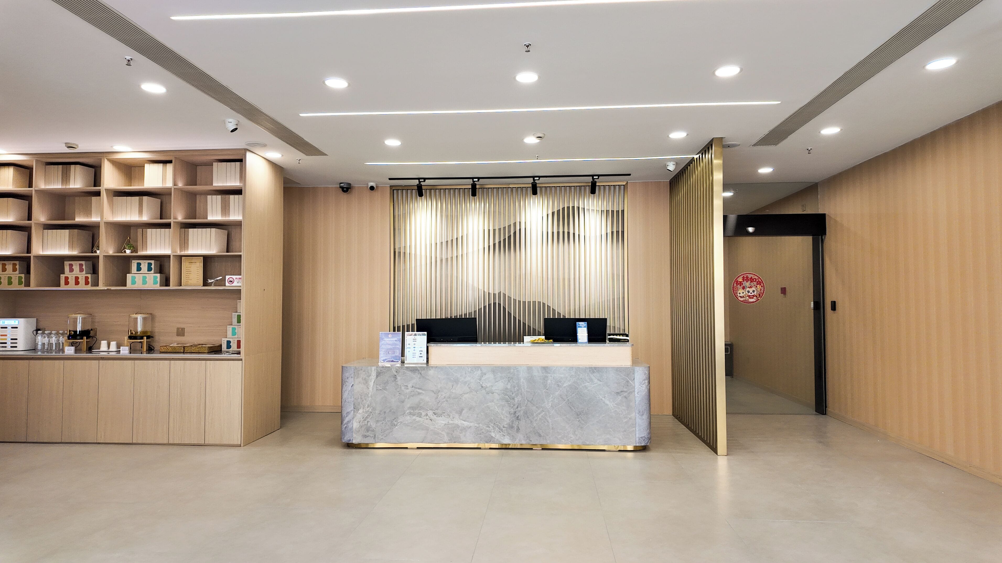 Zona de recepción con mostrador de mármol, estanterías de madera con diversos objetos y un separador de cortinas.