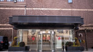 A modern building entrance with a glass door, a metal canopy, and decorative plants. - Shanghai Joyful Star Hotel (Shanghai)