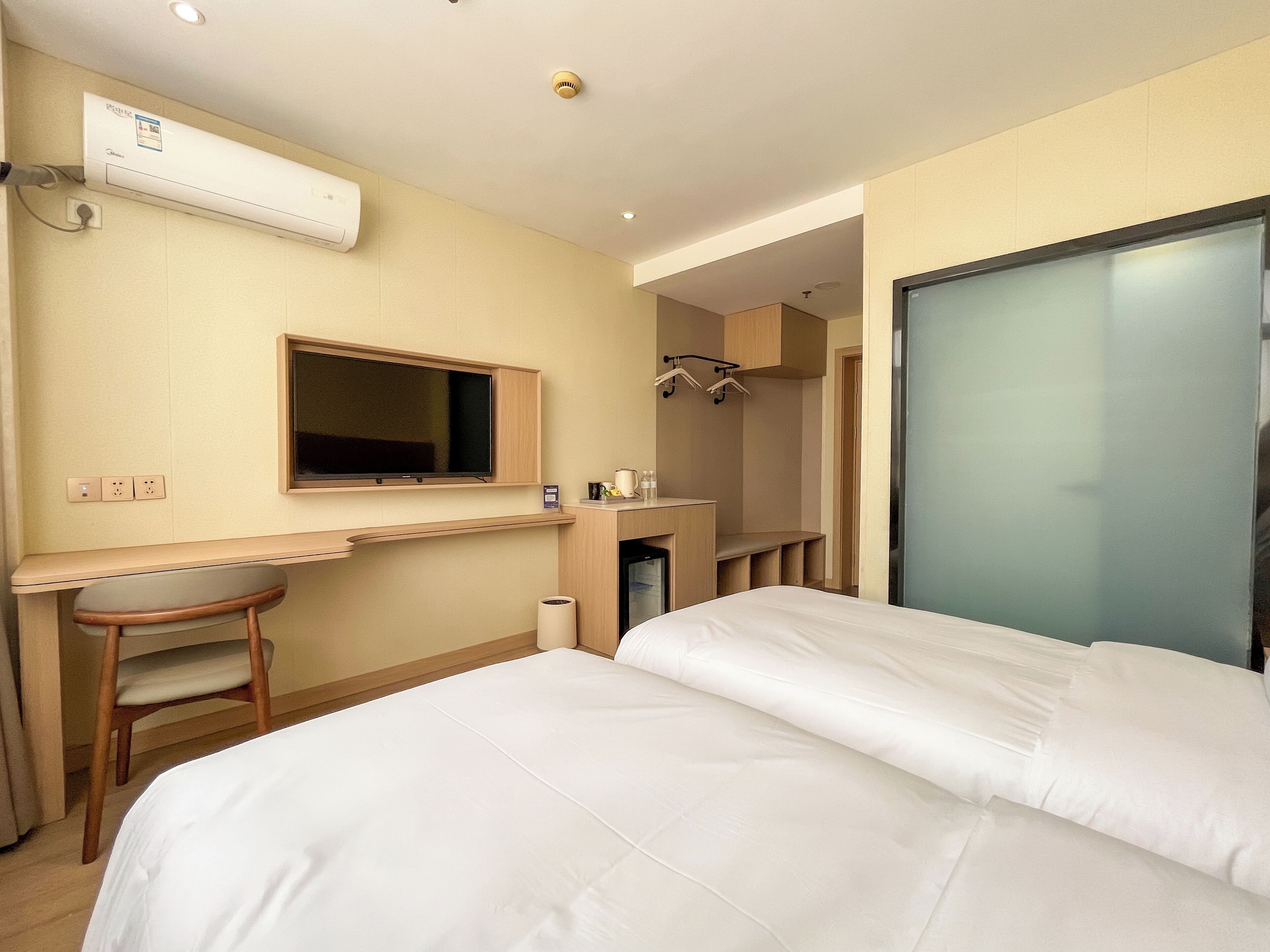 A hotel room with a bed, a desk, a chair, a television, and a wardrobe.