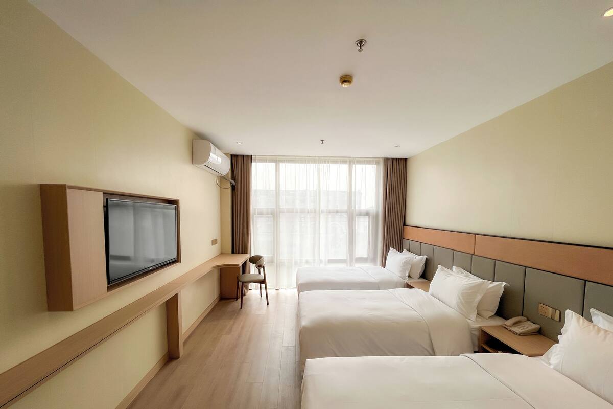 Una habitación de hotel con dos camas, televisión, escritorio y una silla.