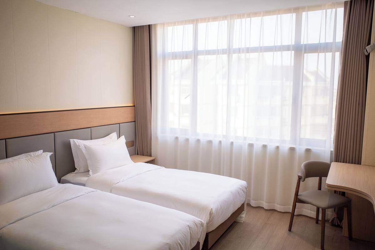 Una habitación de hotel con dos camas, un escritorio y una silla.