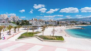 Un paisaje urbano costero con playa, paseo marítimo y edificios modernos.