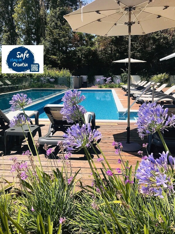 A poolside area with lounge chairs and a sign reading "Safe Croatia".