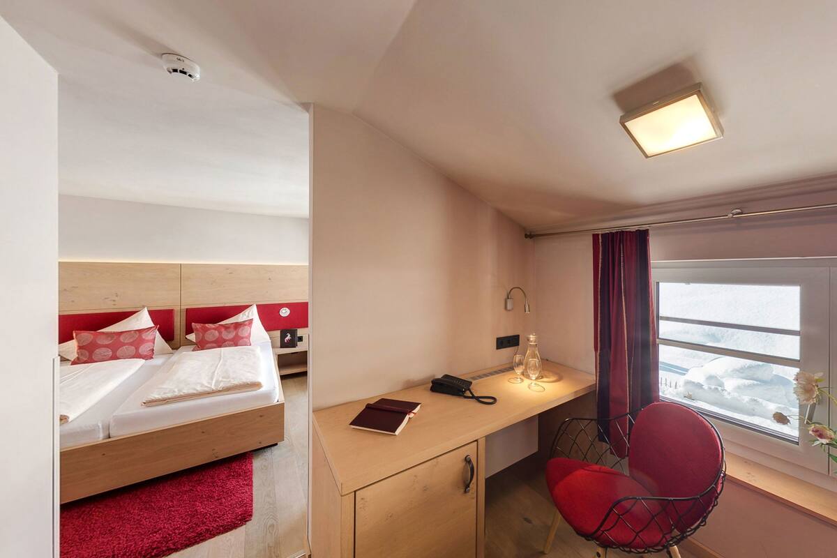 A hotel room with a bed, desk, chair, and window with a view.