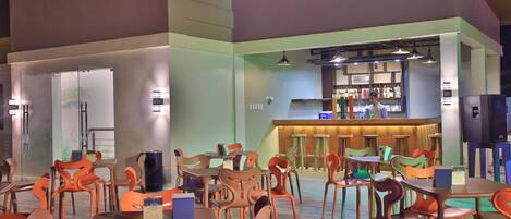 A restaurant with multiple tables and chairs, a bar area, and a counter with a menu.