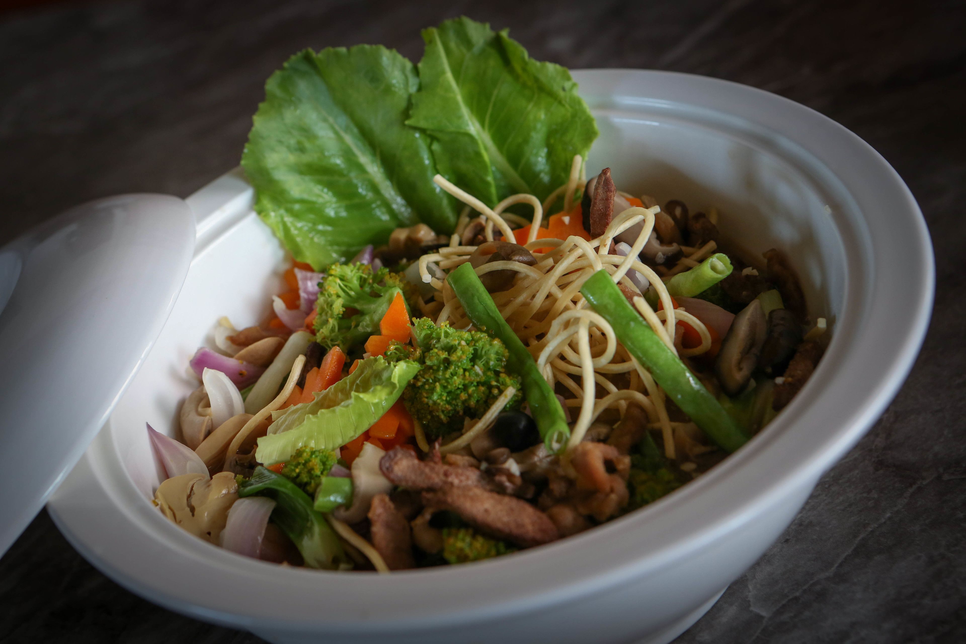 A bowl of noodle dish with vegetables and meat.