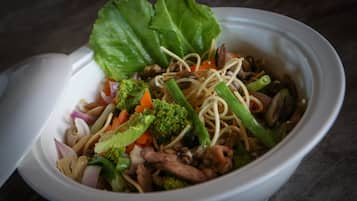 A bowl of noodle dish with vegetables and meat.