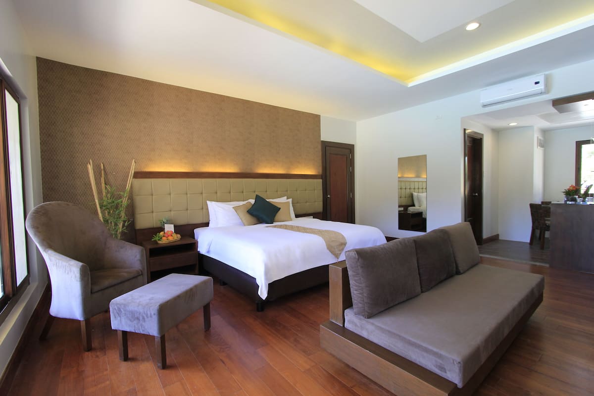 Una habitación de hotel con una cama grande, un sofá, una silla y una mesita.