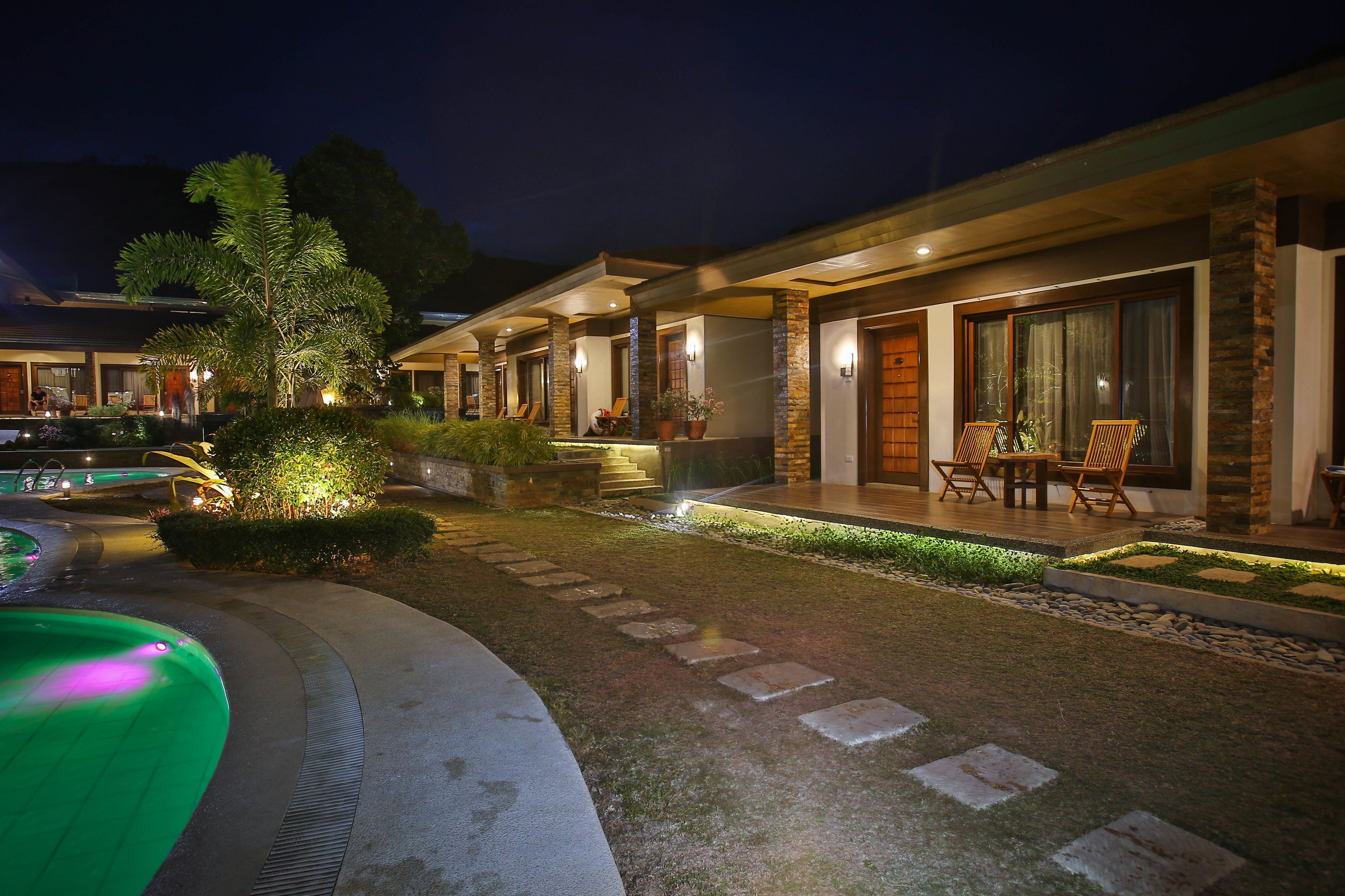 A well-lit outdoor area with a swimming pool, stone pathway, and outdoor seating.