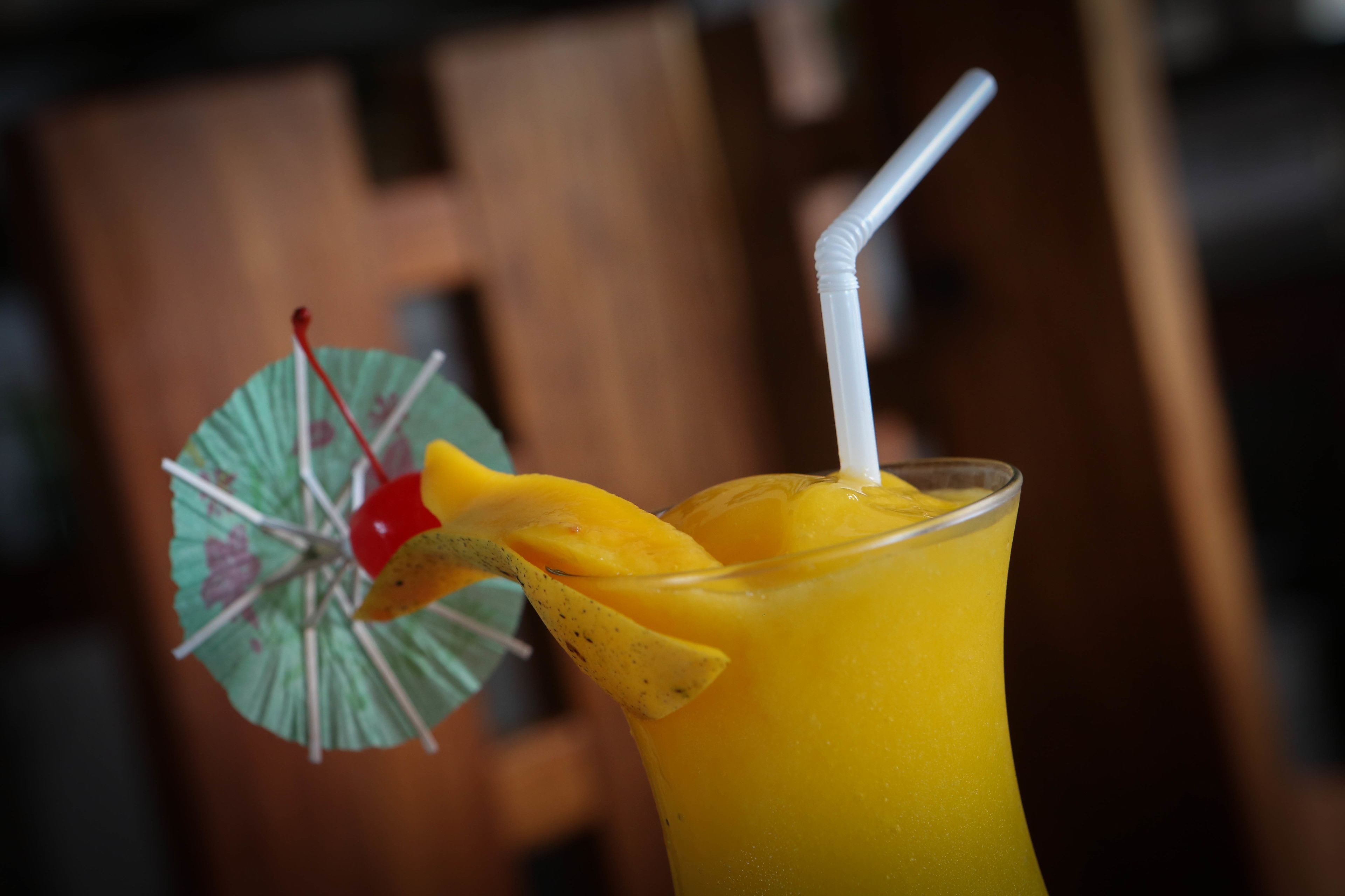 Un vaso de jugo de naranja con pajita y un paraguas decorativo.