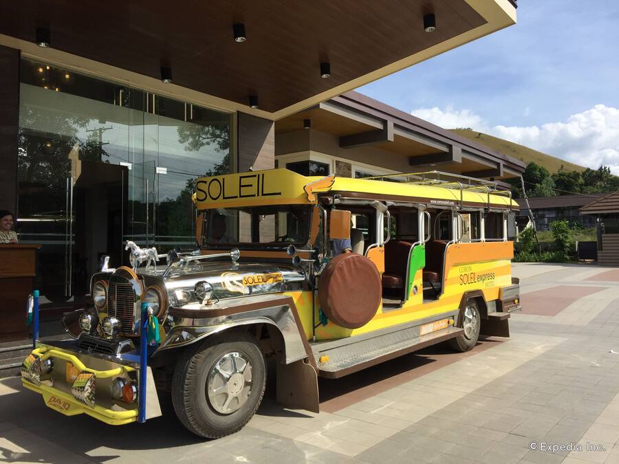 A vintage bus with "SOLEIL" branding parked in front of a modern building.