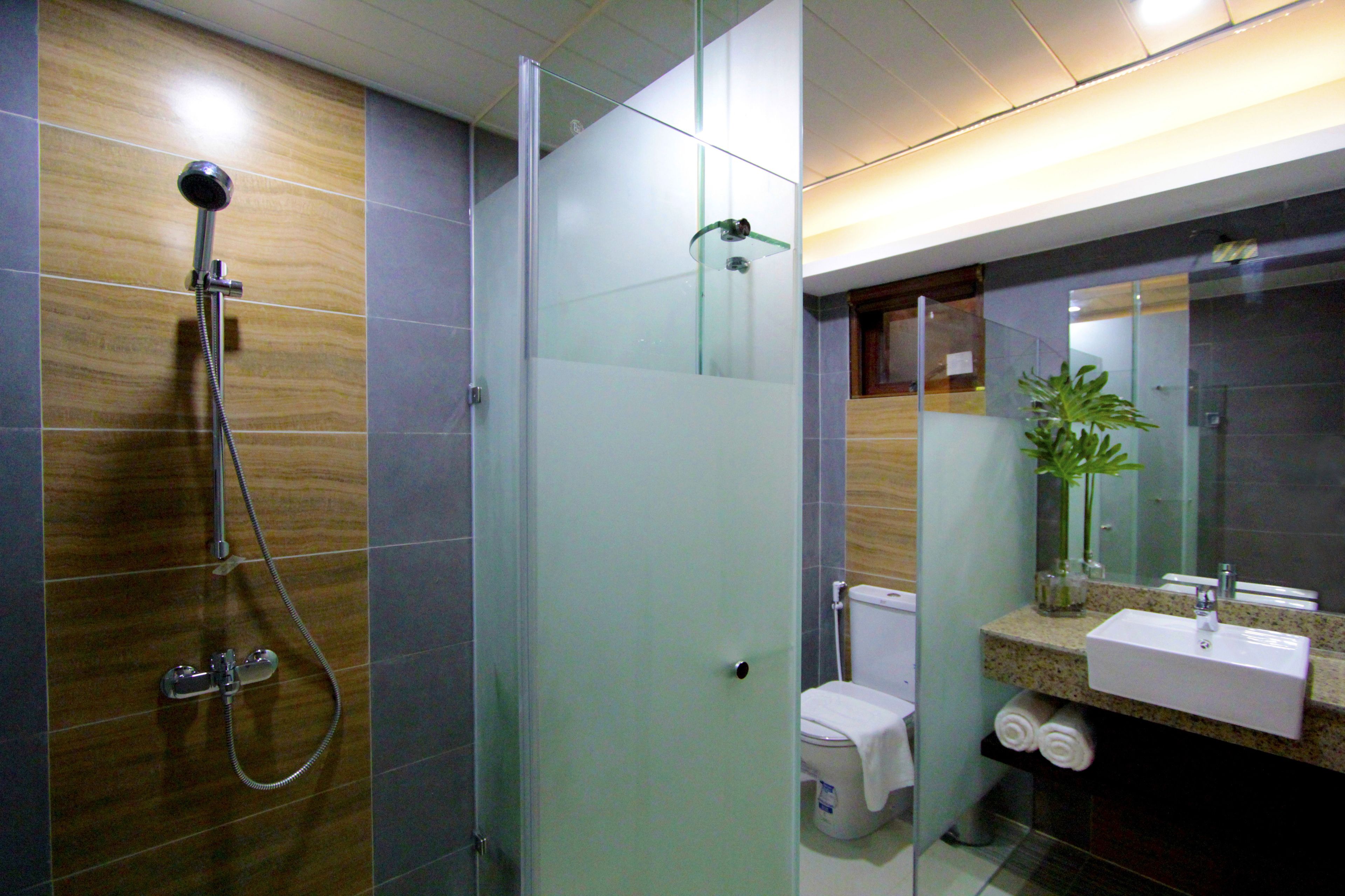 Un baño moderno con ducha de vidrio, inodoro y lavamanos con espejo.