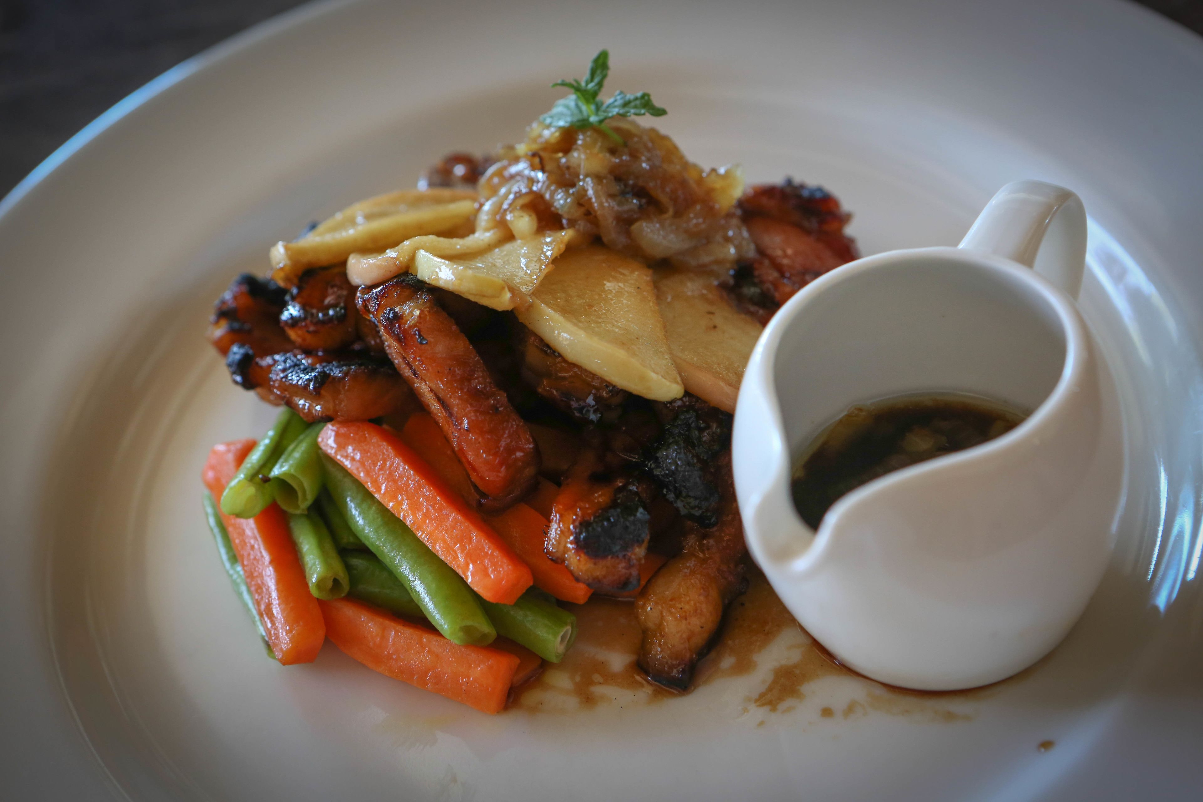 Une assiette de nourriture contenant une variété de légumes et une petite coupelle de sauce.