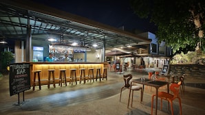 Zona de bar con taburetes y un cartel que muestra las bebidas disponibles.
