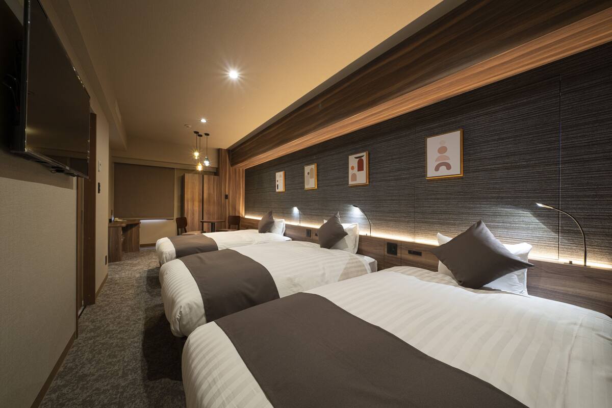 Une chambre d’hôtel avec deux lits, un bureau et une télévision.