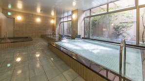 A modern indoor swimming pool with clear glass walls, a tiled floor, and a wooden deck area. - Nagoya B's Hotel (Nagoya)
