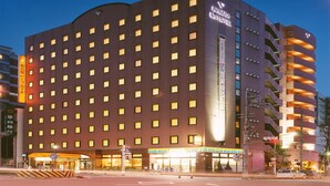 A multi-story hotel with a modern design, featuring a prominent entrance with a sign, multiple windows, and a corner parking structure. - Nagoya B's Hotel (Nagoya)