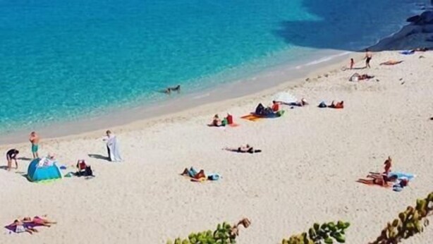 A beach with clear blue water, sandy shore, and a few tents and umbrellas. - La Valle Verde (Zambrone)