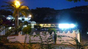 A hotel with a white exterior, a covered outdoor area, and a view of a mountainous landscape. - La Valle Verde (Zambrone)