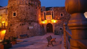 A stone building with a round tower, a bench, and a railing. - La Valle Verde (Zambrone)