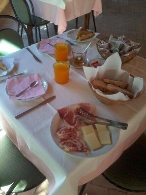 A breakfast table with plates of food, glasses of orange juice, and a basket of bread. - La Valle Verde (Zambrone)